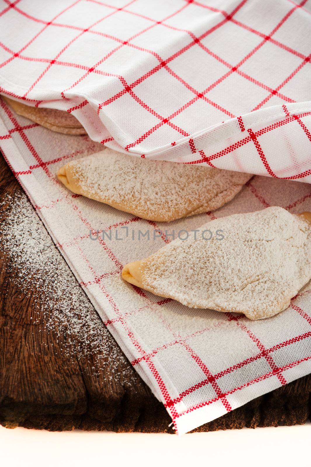 Raw Pierogi (Polish dumplings) on wooden board and kitchen towel
