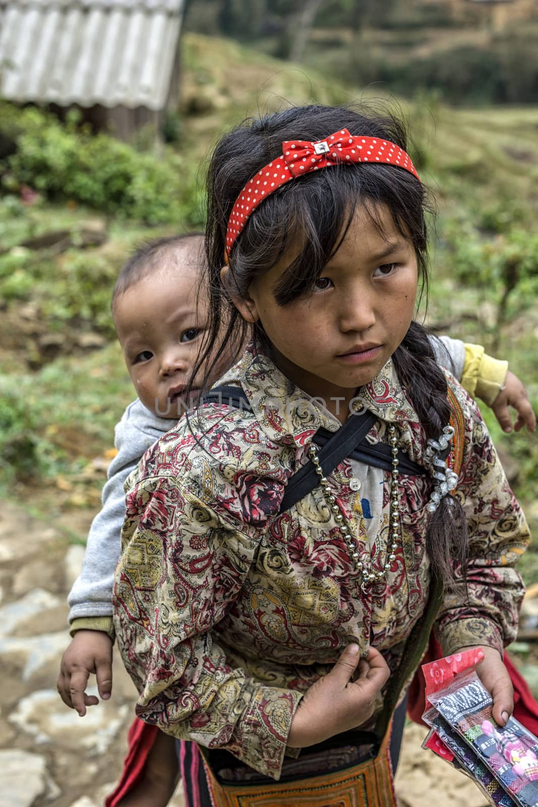 Vietnam Cat Cat - March 2012: Young girl with baby on her back p by Claudine