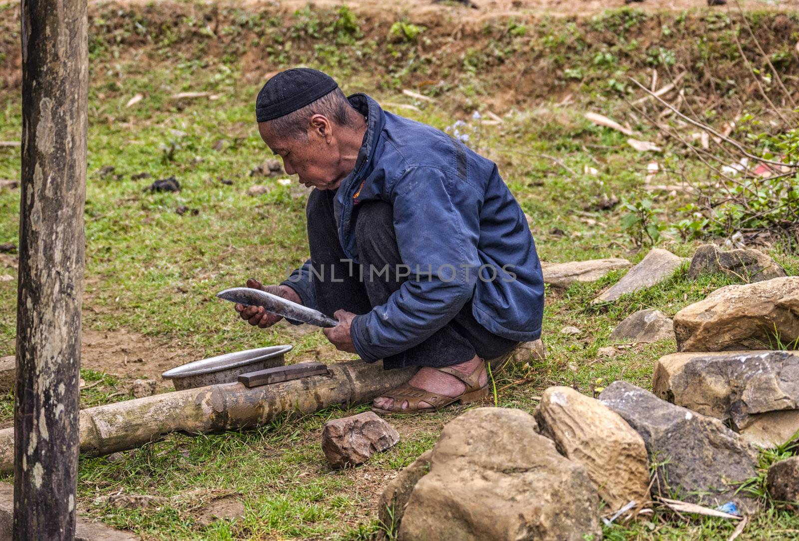 Vietnam Cat Cat - March 2012: Man sharping long knife. by Claudine