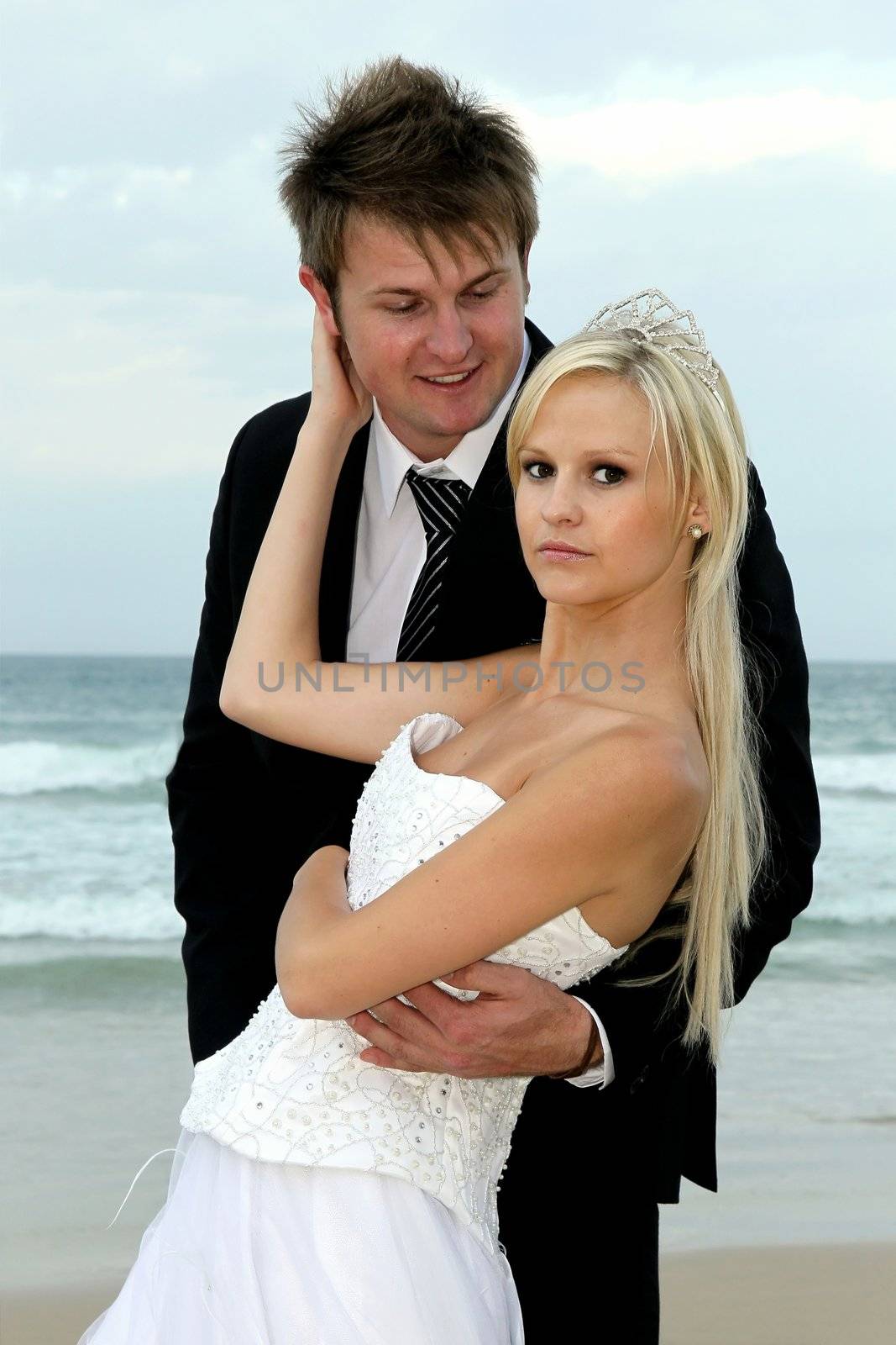 Pretty blond bride and her handsome groom at the sea shore