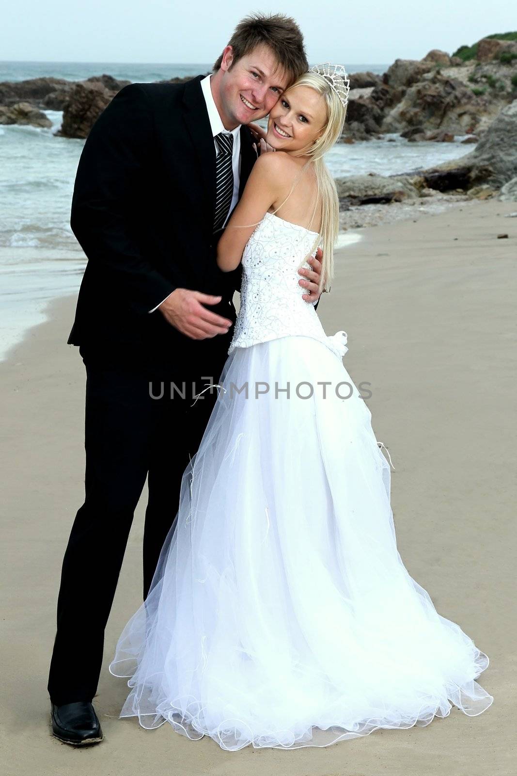 Pretty blond bride and her handsome groom at the sea shore