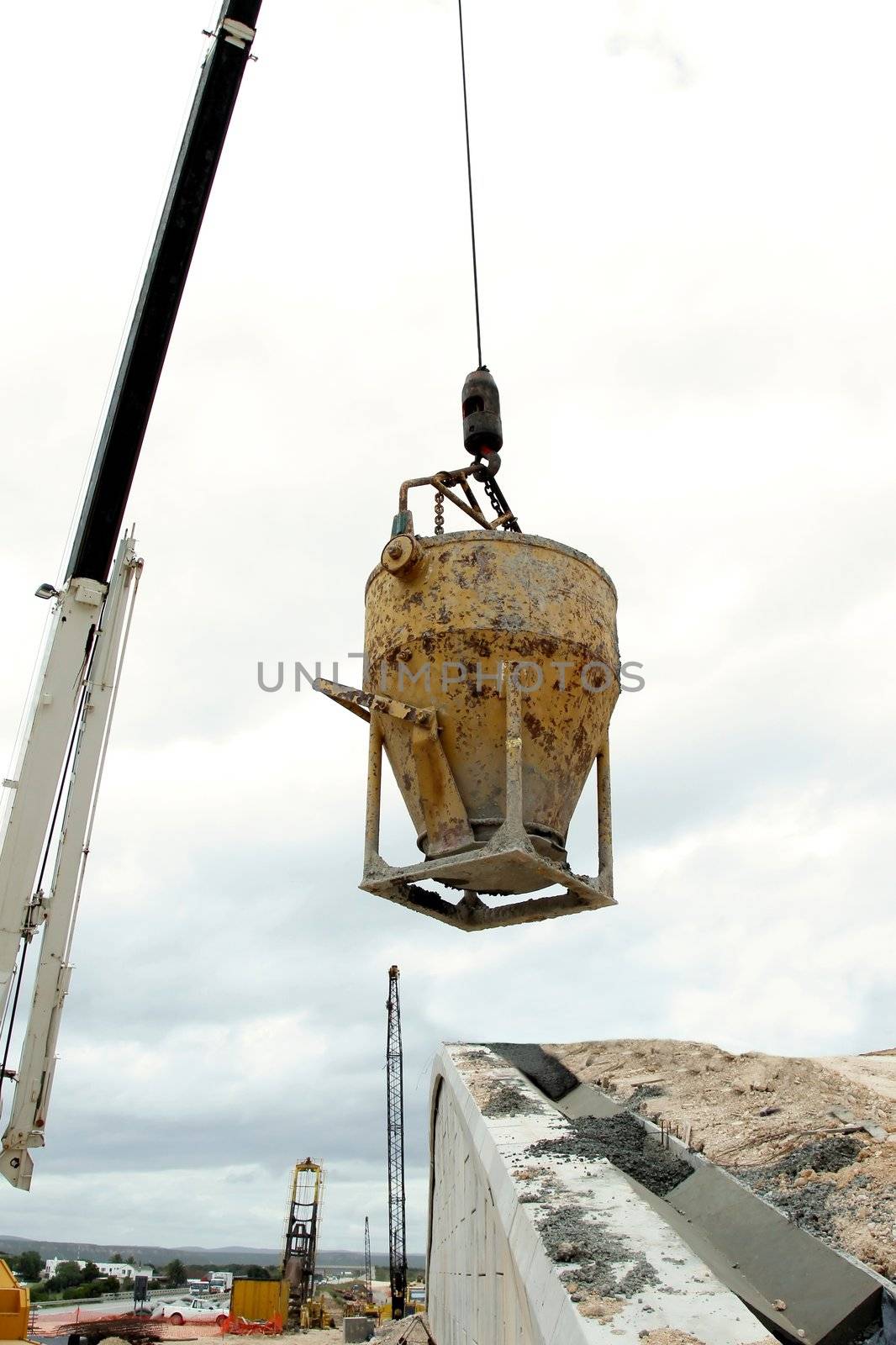 Steel bucket filled with concrete being lifted by a crane on a construction site