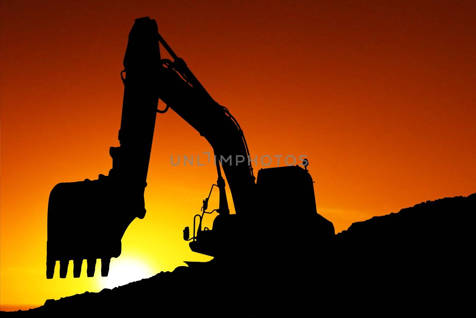 Silhouette of a digging machine at sunset