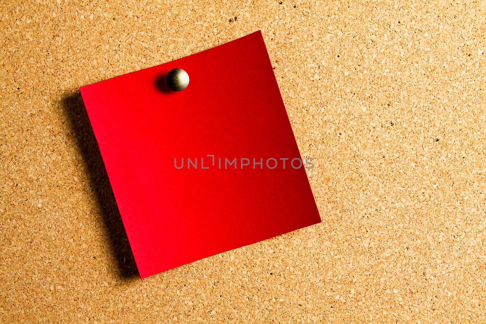 red post-it hanging on a red panel of cork