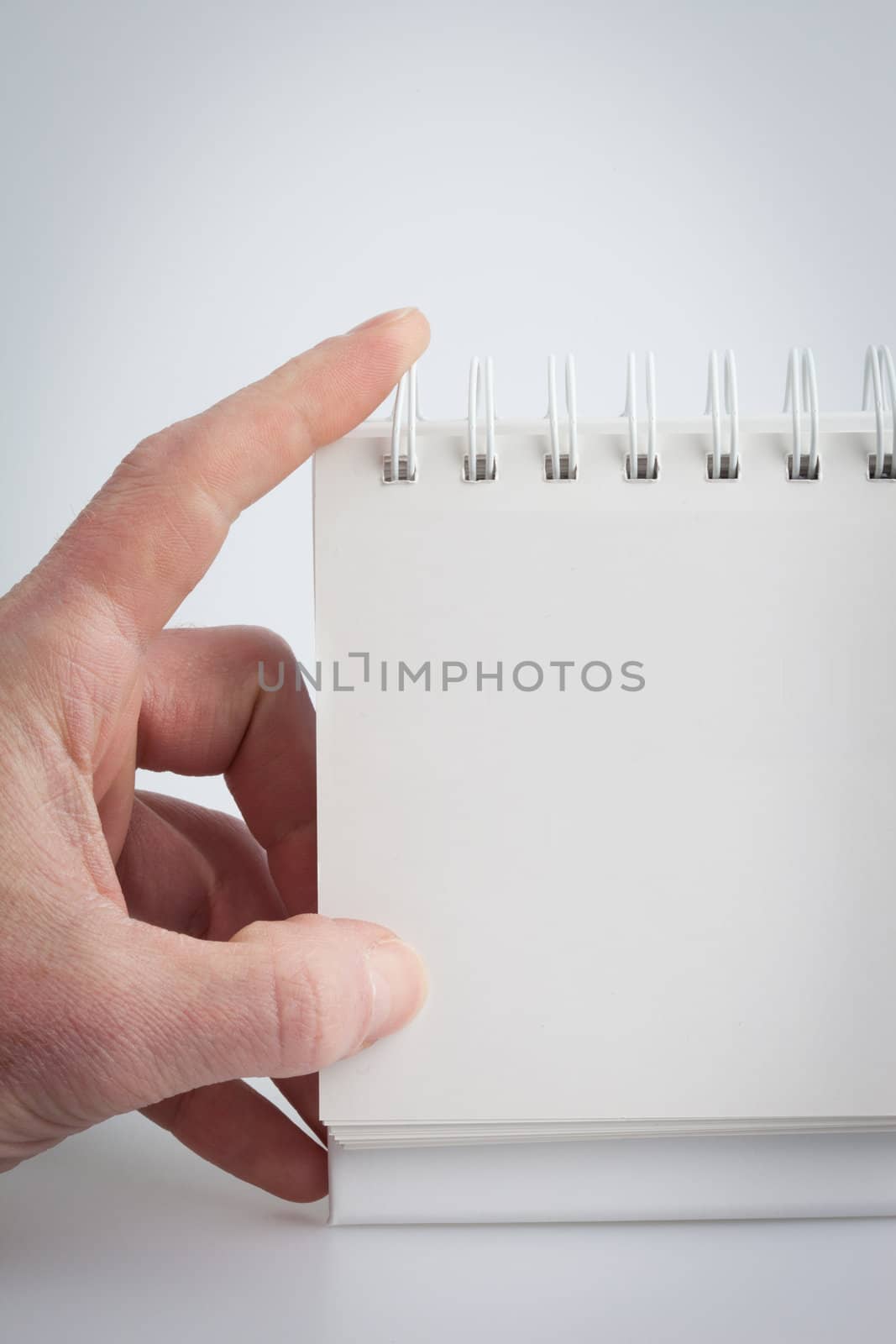 Hand holding a blank note pad on a white background