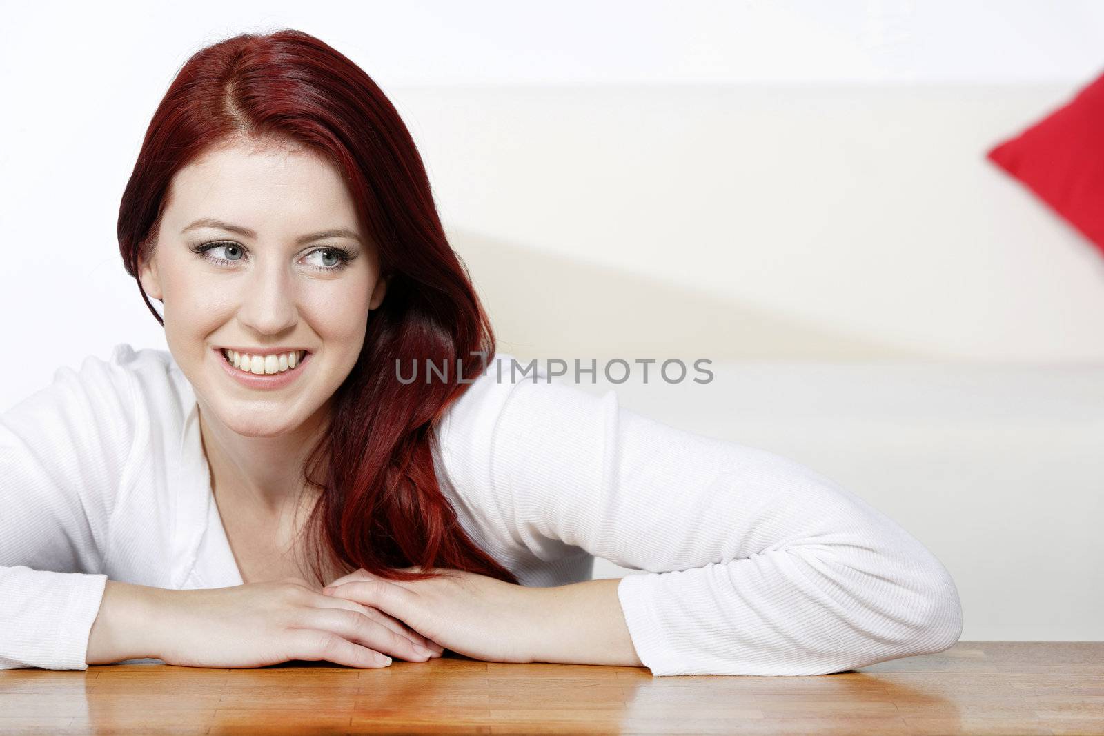 Beautiful young woman resting on a coffee table in front of sofa at home.