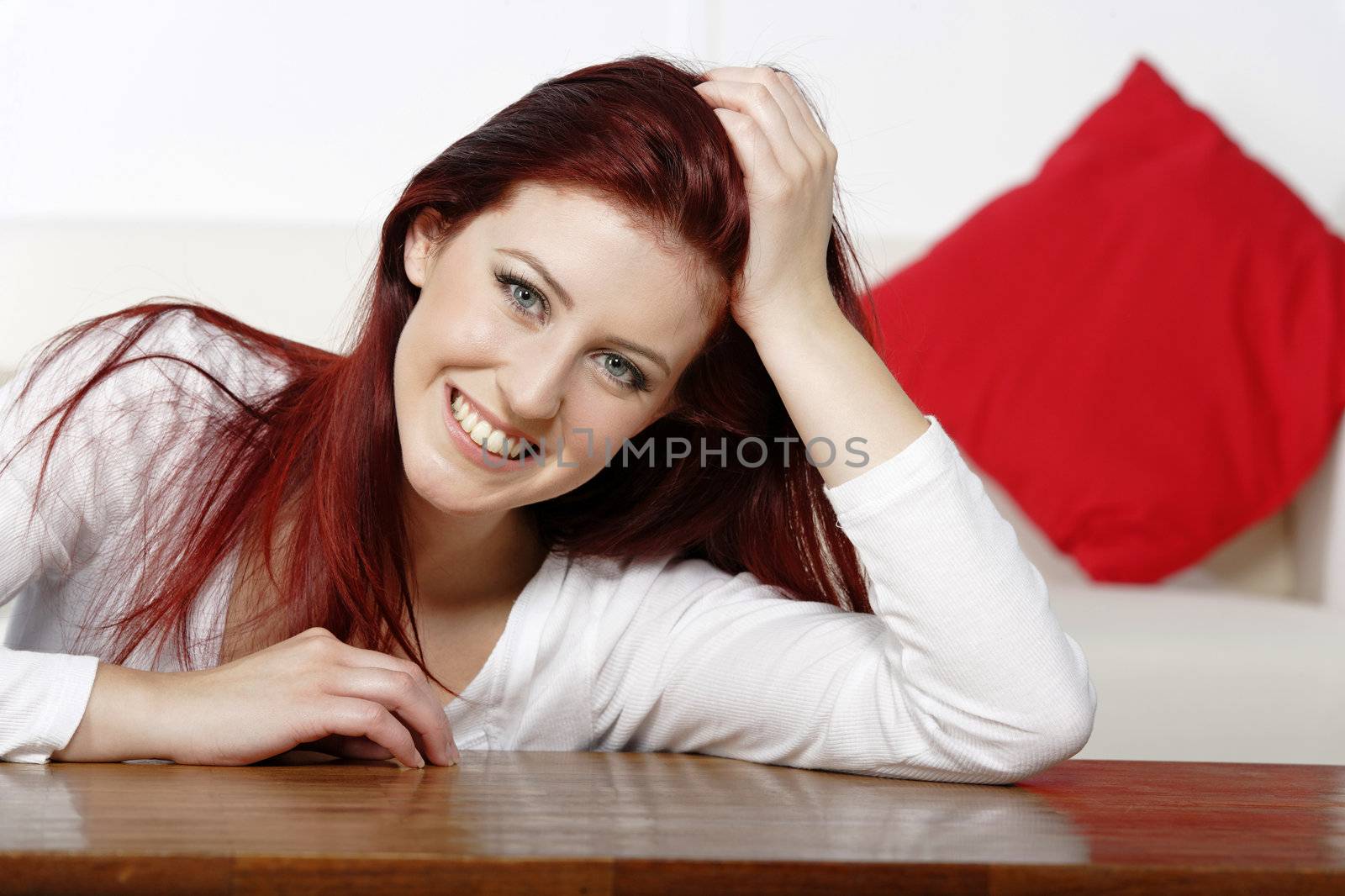 Beautiful young woman resting on a coffee table in front of sofa at home.