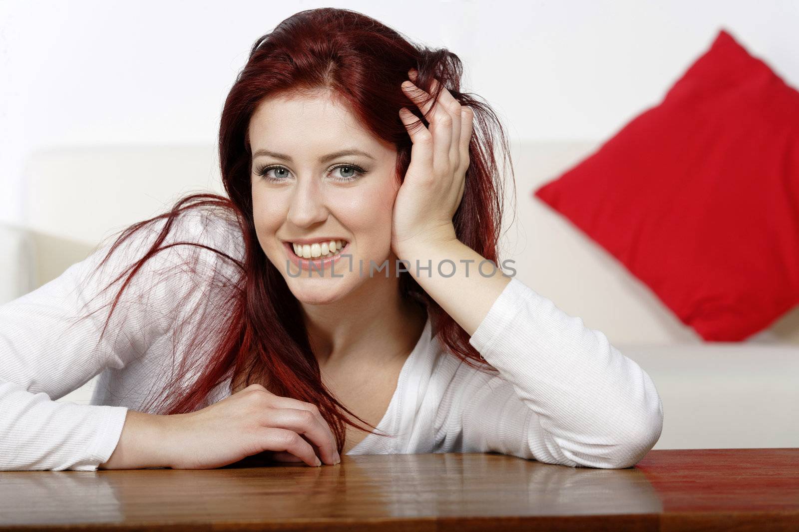 Beautiful young woman resting on a coffee table in front of sofa at home.