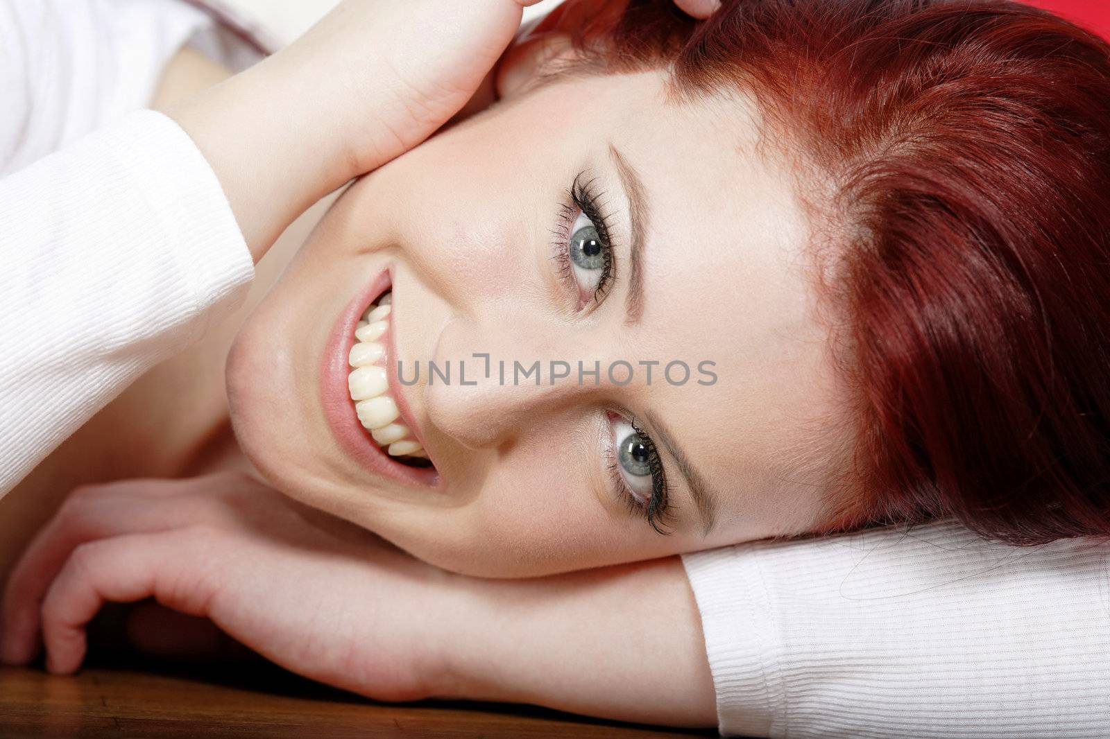 Beautiful young woman resting on a coffee table in front of sofa at home.