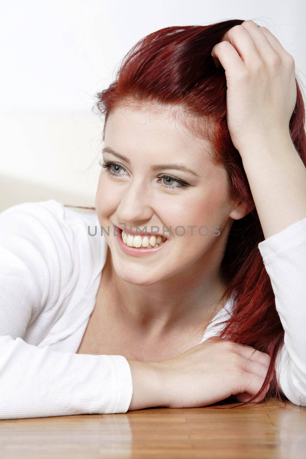 Beautiful young woman resting on a coffee table in front of sofa at home.