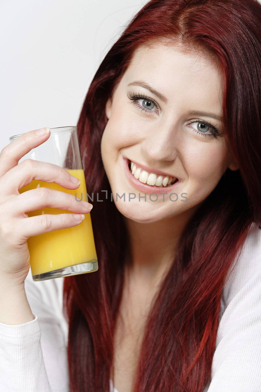 Smiling happy young woman with a fresh glass of Orange juice during breakfast.