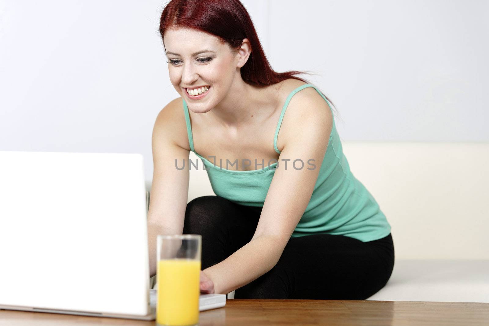 Happy smiling woman chatting with friends on a laptop at home on the sofa