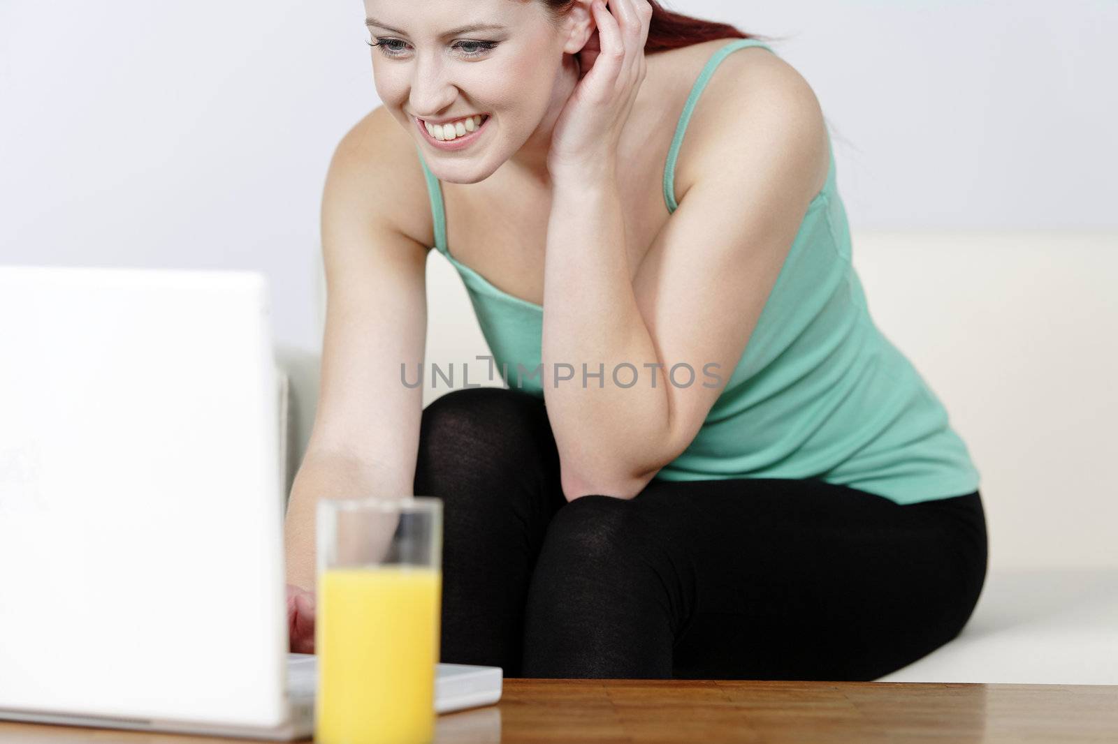 Young woman using laptop at home by studiofi