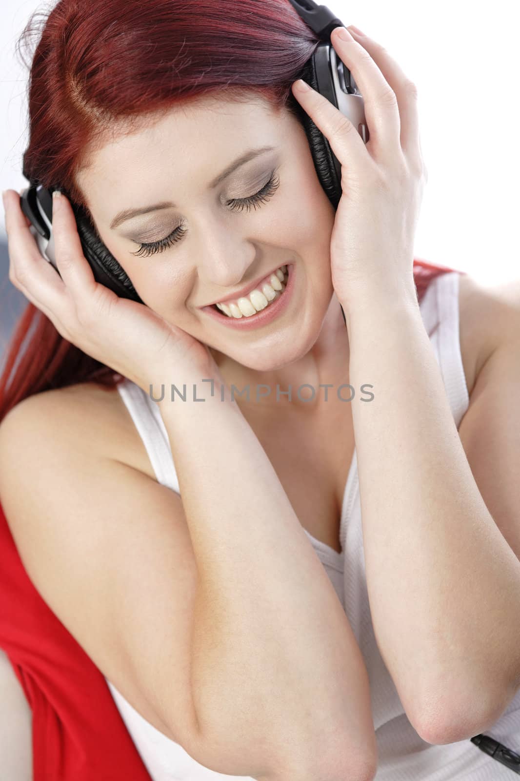 Happy smiling young woman listening to music at home on headphones