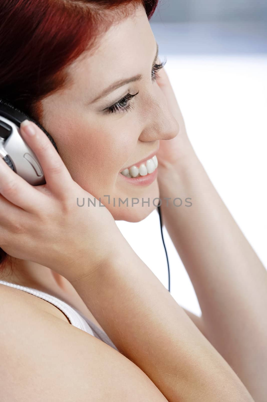 Happy smiling young woman listening to music at home on headphones