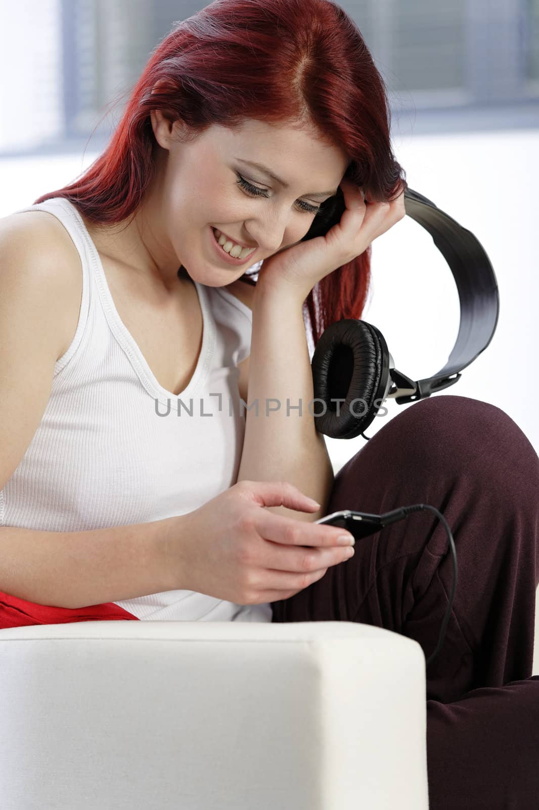 Happy smiling young woman listening to music at home on headphones