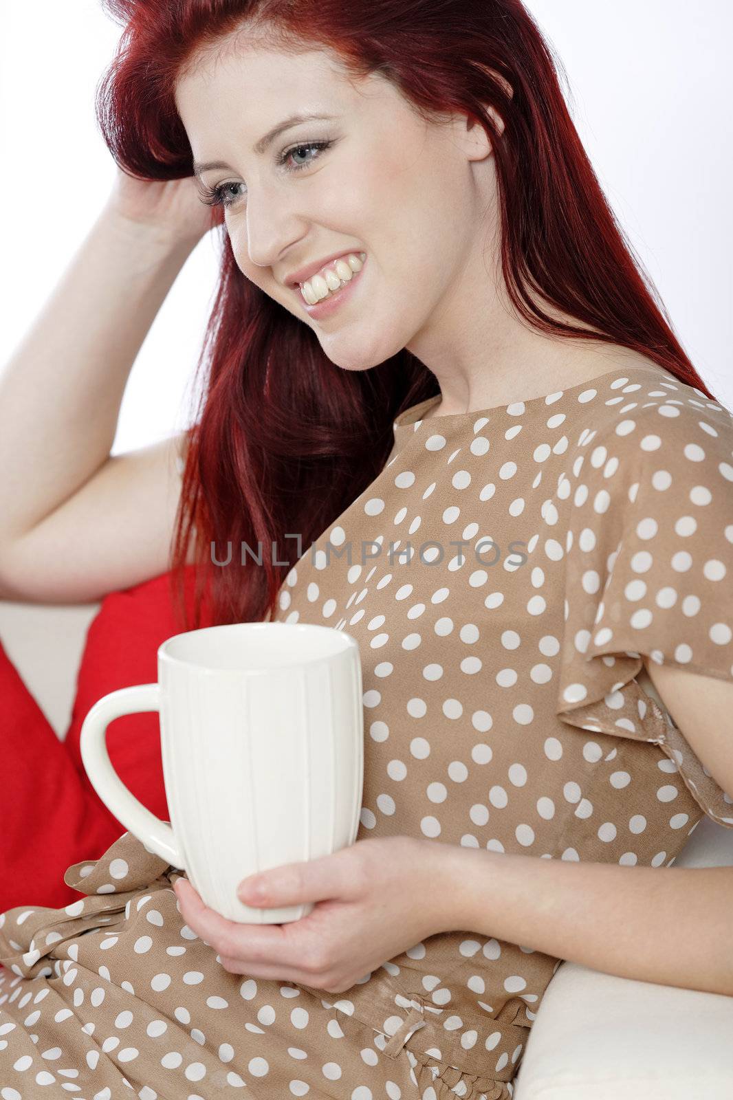 Woman relaxing with hot drink on sofa by studiofi