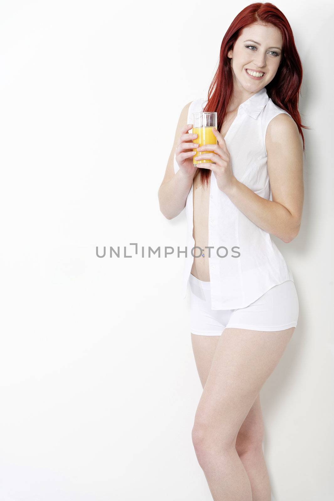 Beautiful young woman in white shirt and underwear enjoying some breakfast Orange juice.