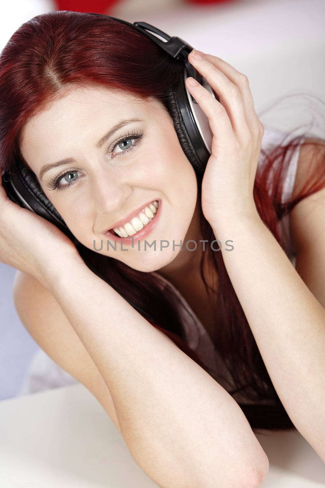 Beautiful young woman lying on her sofa at home listening to music on her headphones
