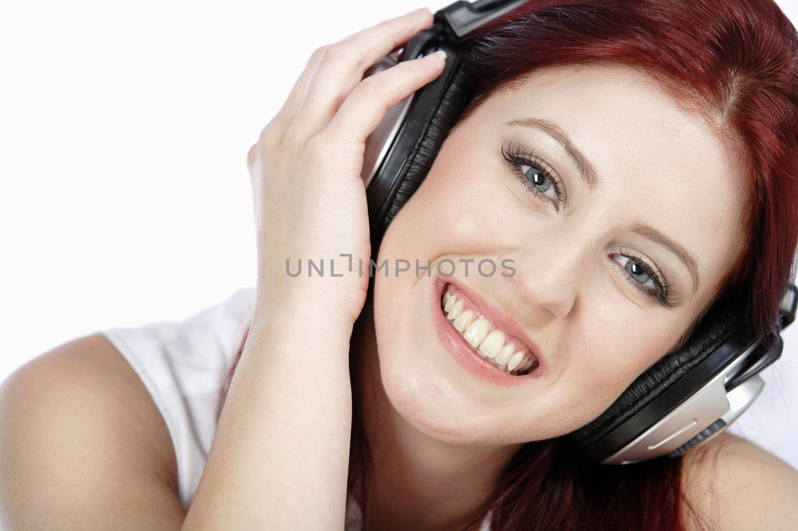 Beautiful young woman lying on her sofa at home listening to music on her headphones