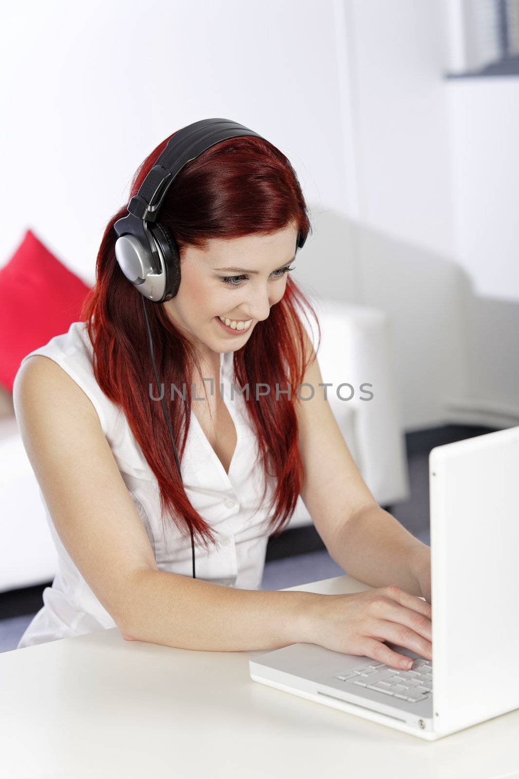 Beautiful woman working on laptop listening to music on her heaphones