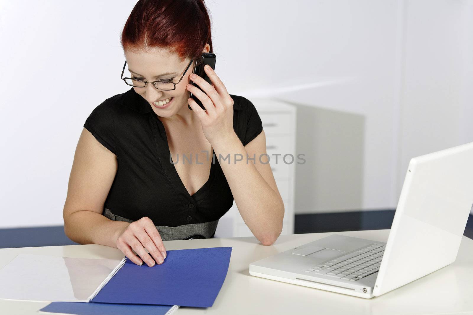 Beautiful young woman talking on her mobile phone at work