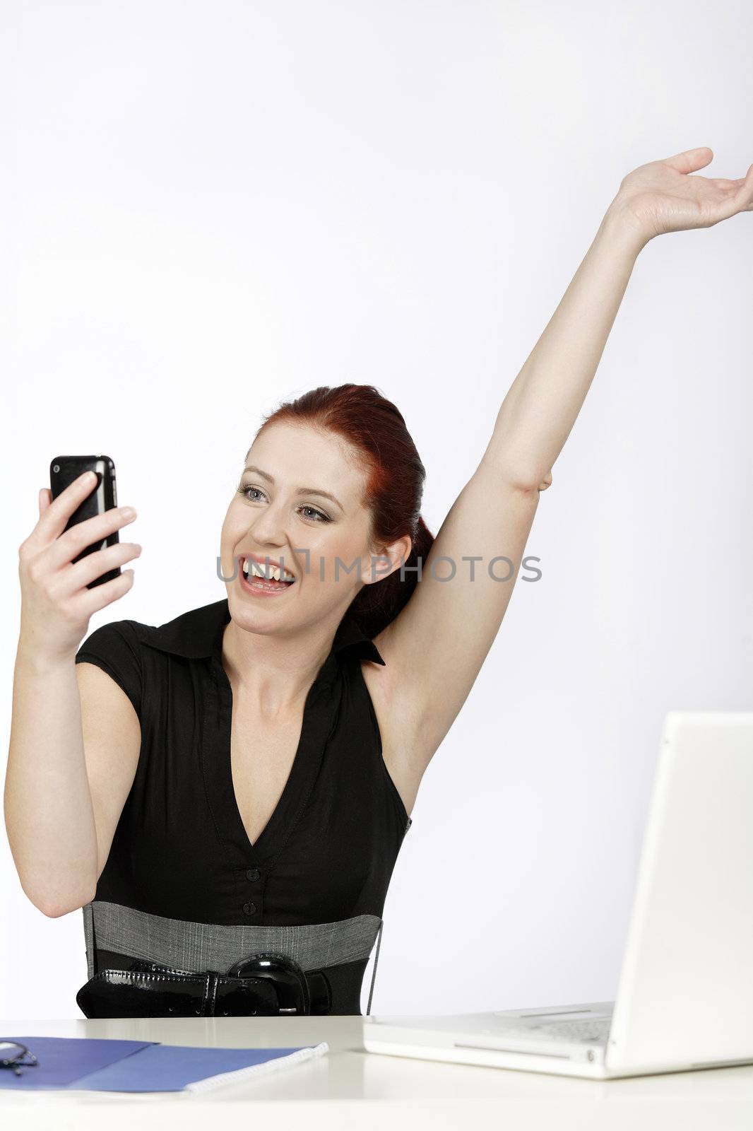 Professional young woman receiving good news on her mobile at work