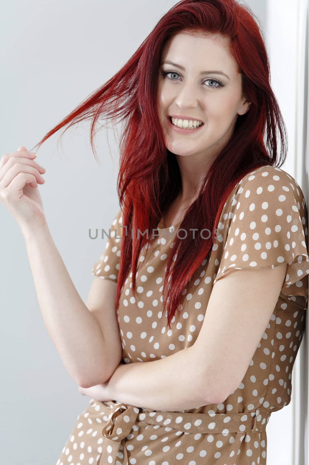 Beautiful happy young woman in a summer dress leaning against a wall.