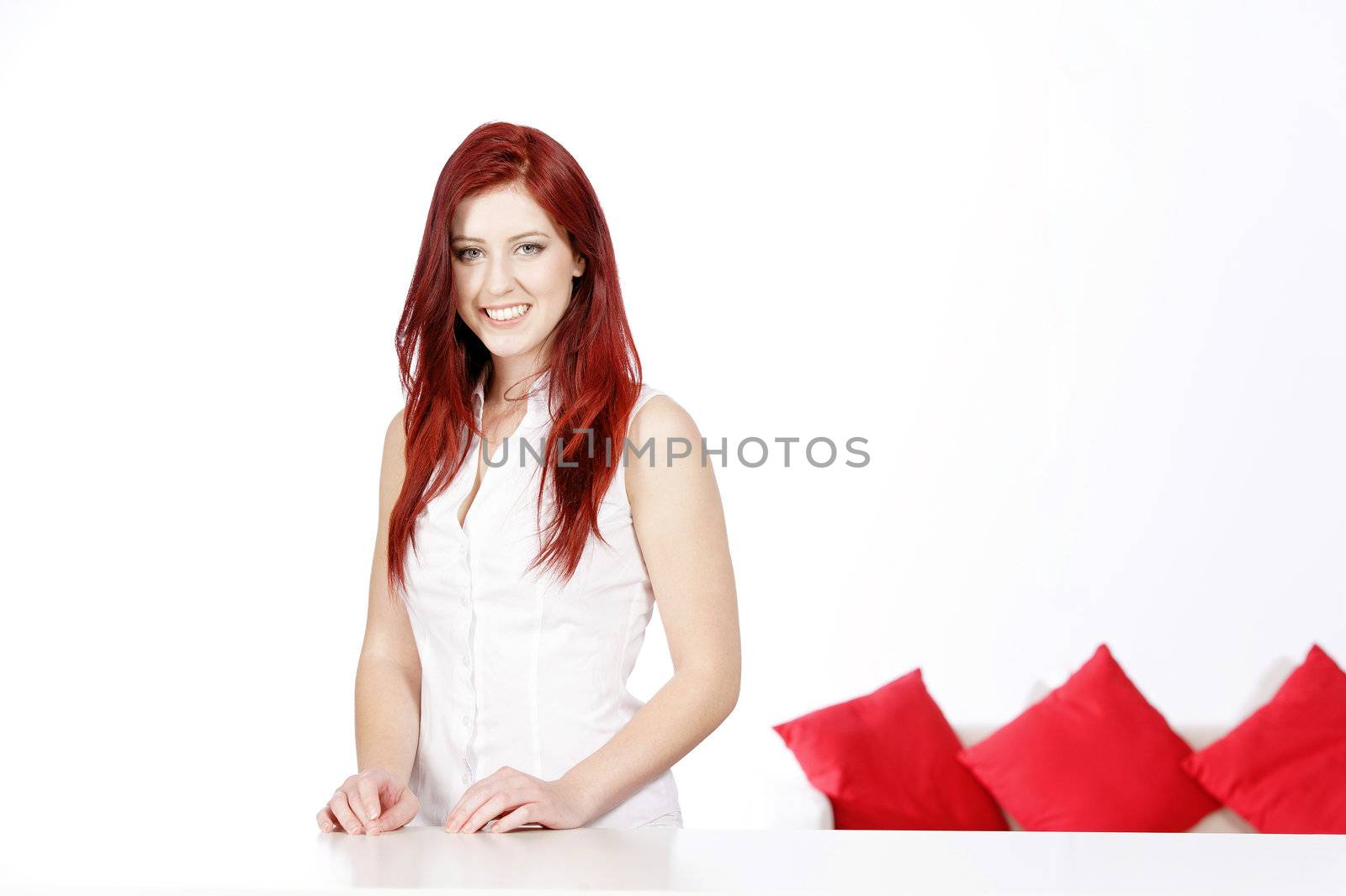 Beautiful young woman leaning on a table at home with a sofa in the background.