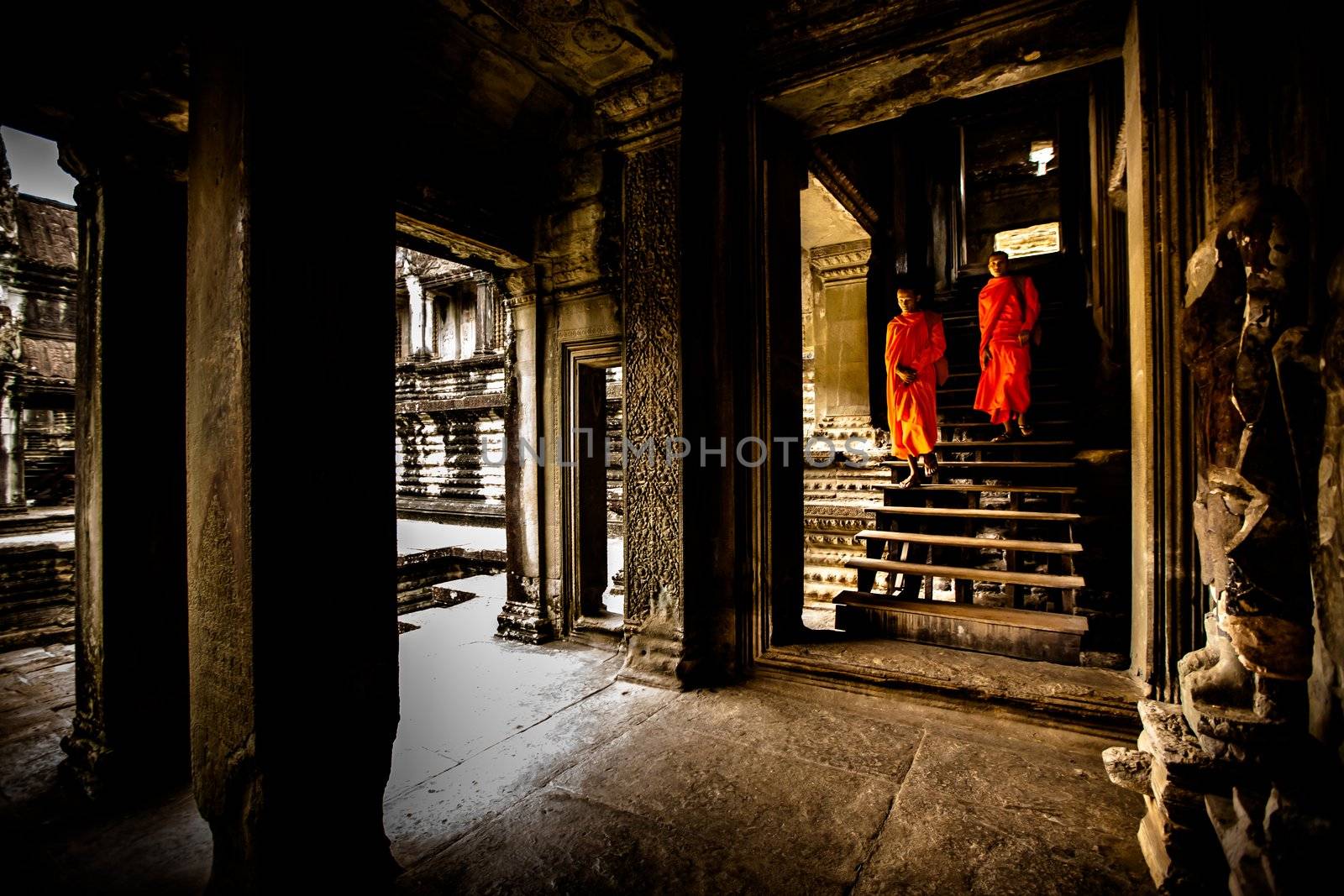 Unidentified buddhist monks walk in the ruin of Angkor. The monastery is still use as part of worship sacred place.