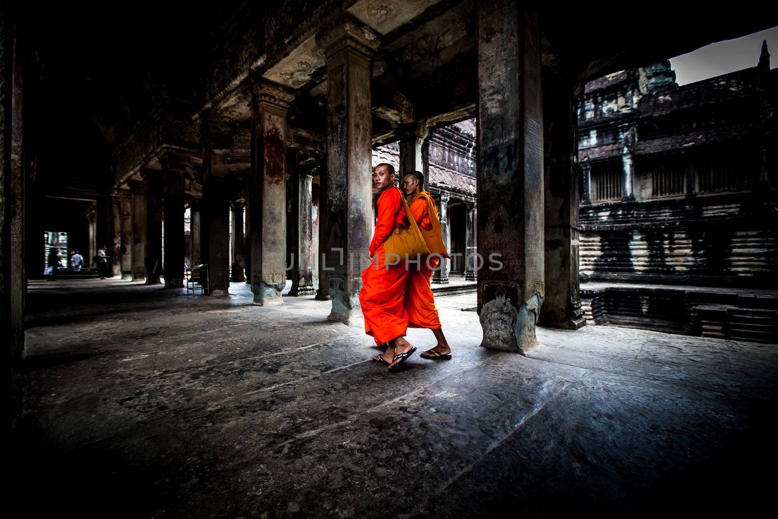 Unidentified buddhist monks walk in the ruin of Angkor. The monastery is still use as part of worship sacred place.