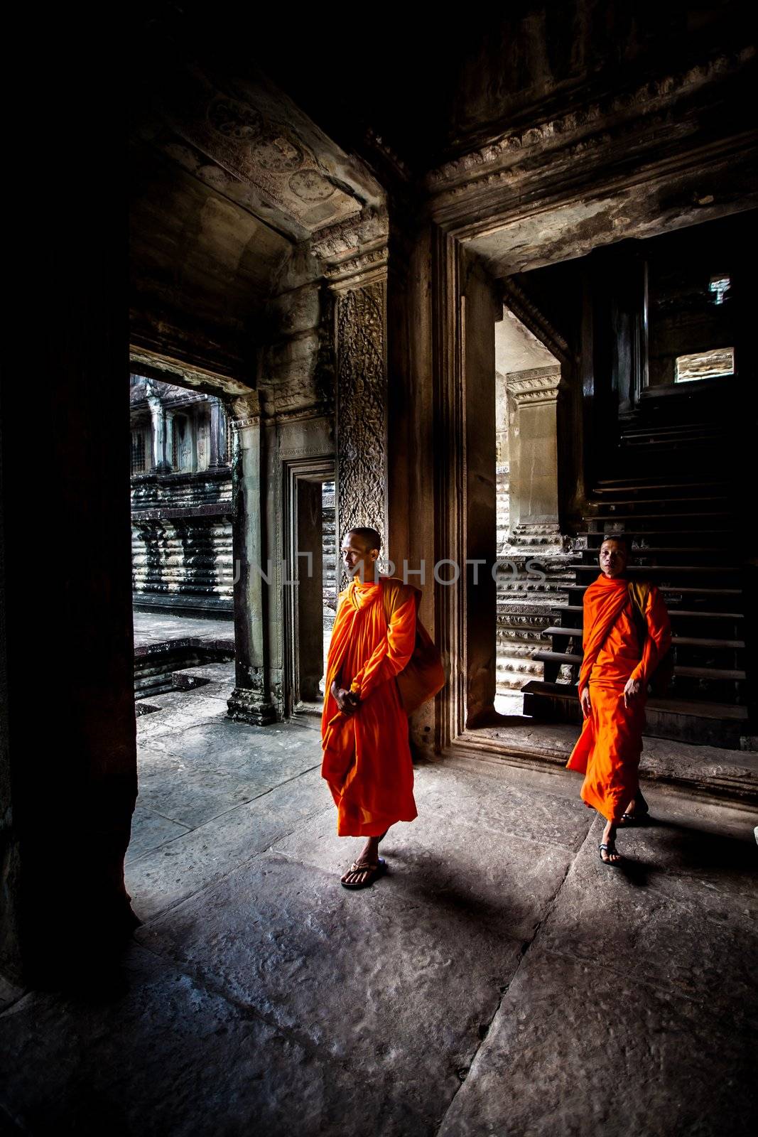 Unidentified buddhist monks walk in the ruin of Angkor. The monastery is still use as part of worship sacred place.