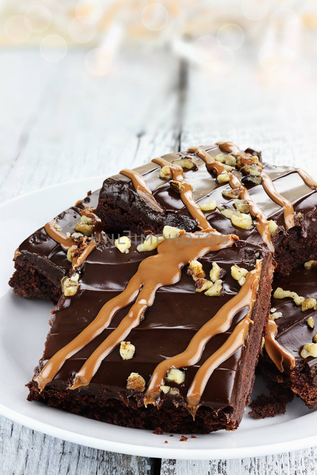 Close up plate of brownies with nuts and caramel sauce.