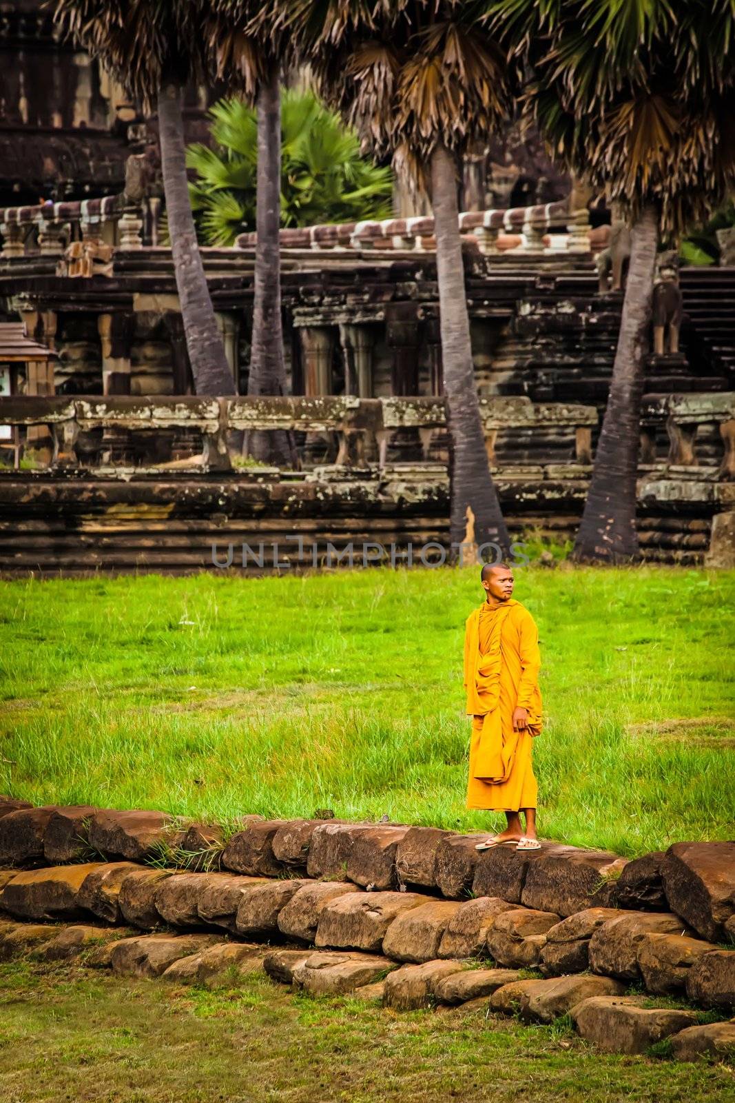 SIEM REAP, CAMBODIA - CIRCA JUNE 2012: Unidentified buddhist monk standing on the edge of the pool circa June 2012 in Angkor Wat, Cambodia The monastery is still use as part of worship sacred place.