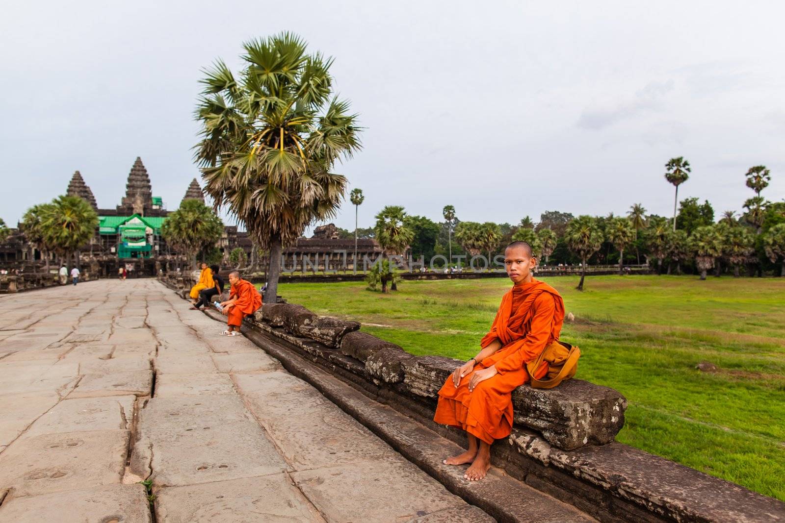 SIEM REAP, CAMBODIA - CIRCA JUNE 2012: Unidentified buddhist monk sits on the edge of the causeway/walkway circa June 2012 in Angkor Wat, Cambodia The monastery is still use as part of worship sacred place.