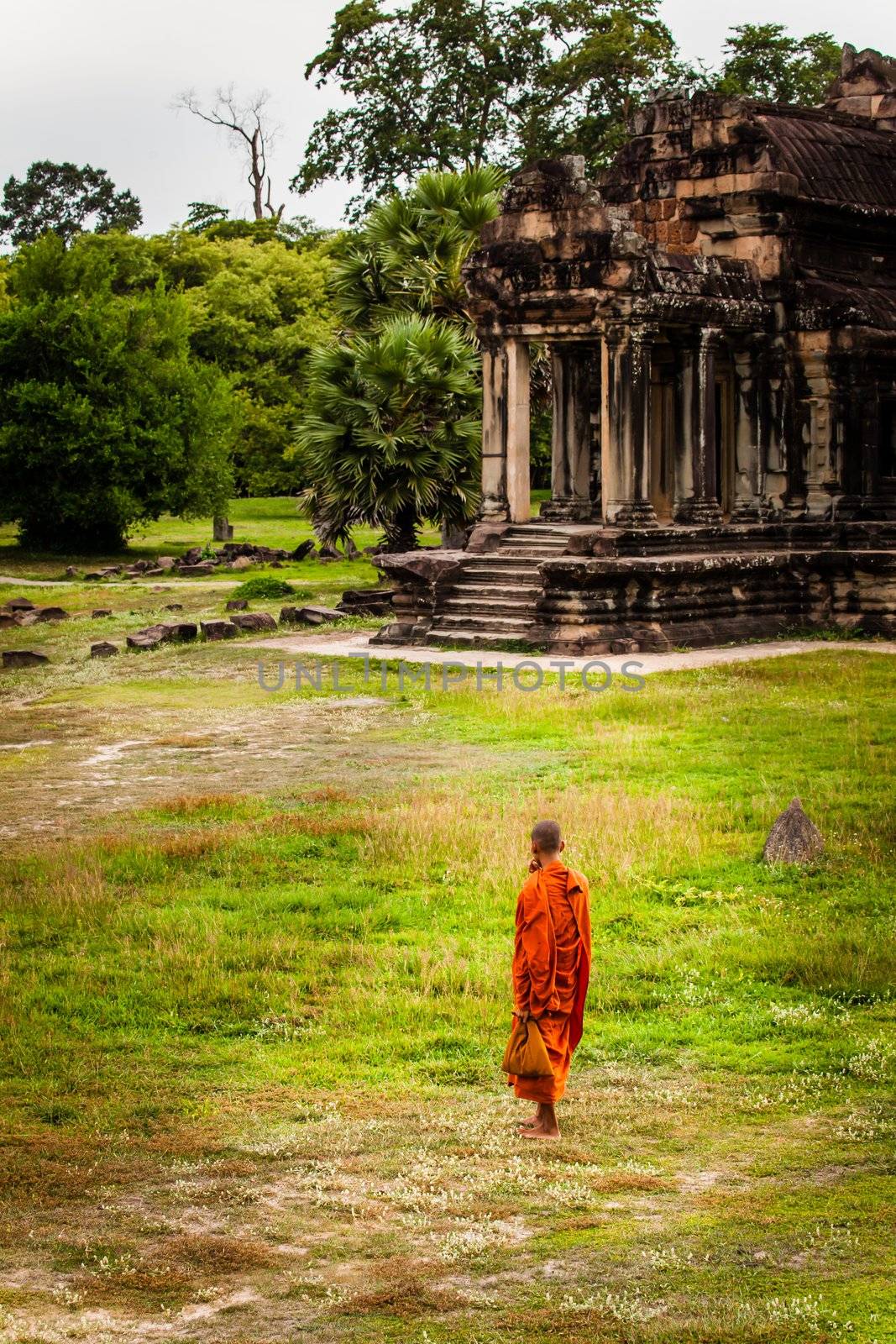 SIEM REAP, CAMBODIA - CIRCA JUNE 2012: Unidentified buddhist monk standing in the field circa June 2012 in Angkor Wat, Cambodia The monastery is still use as part of worship sacred place.