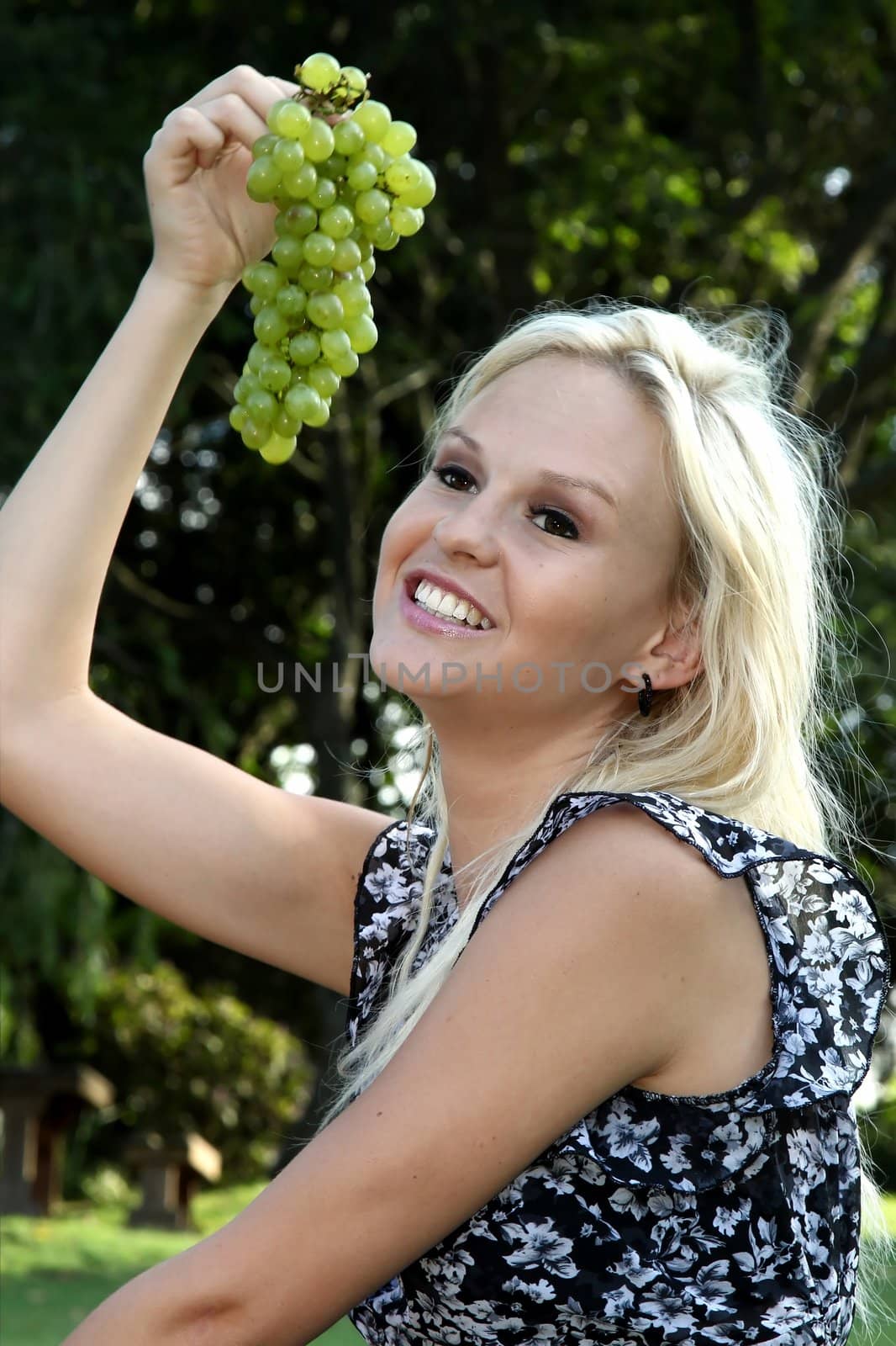 Lovely pretty blonde girl with a big bunch of green grapes