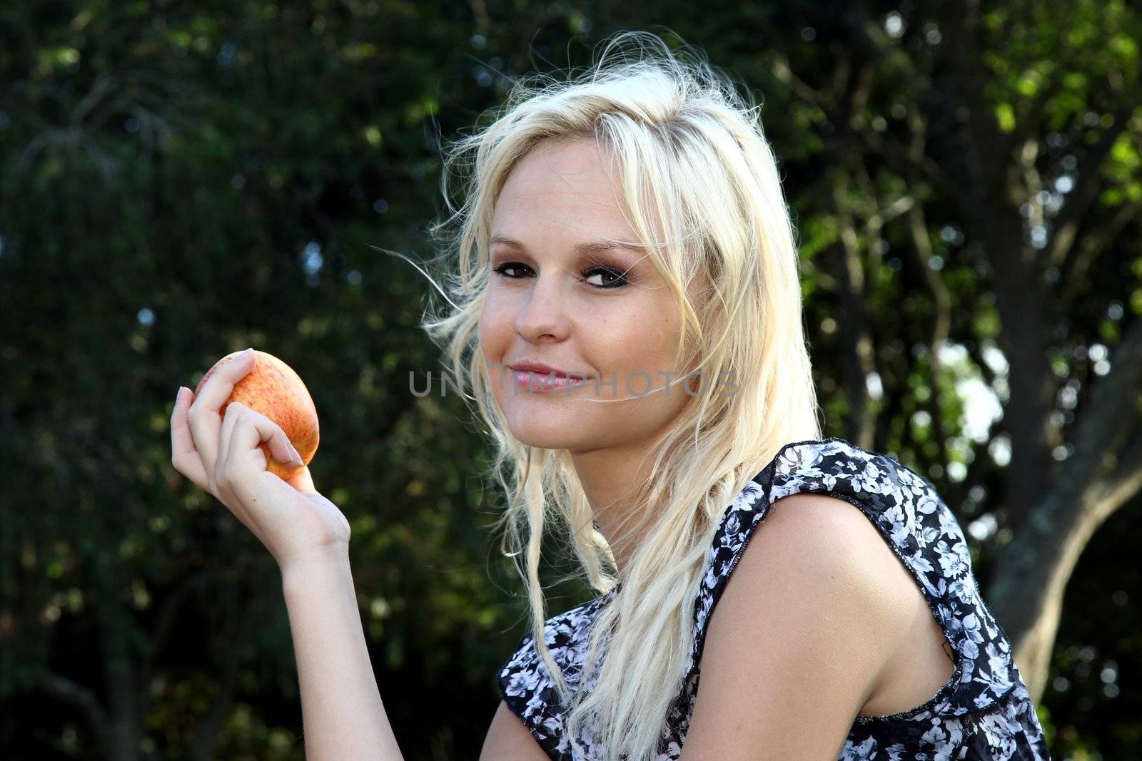 Gorgeous smiling blonde woman holding a juicy apple