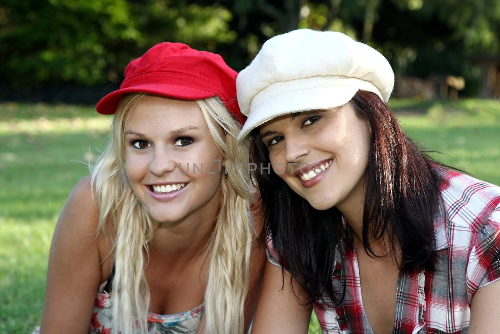 Two gorgeous smiling young women friends in caps