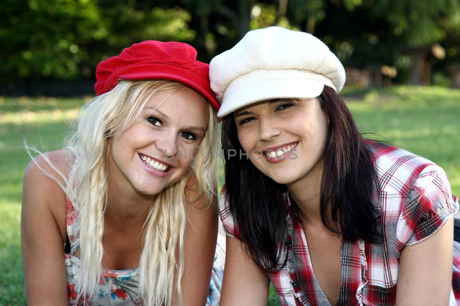 Two gorgeous smiling young women friends in caps