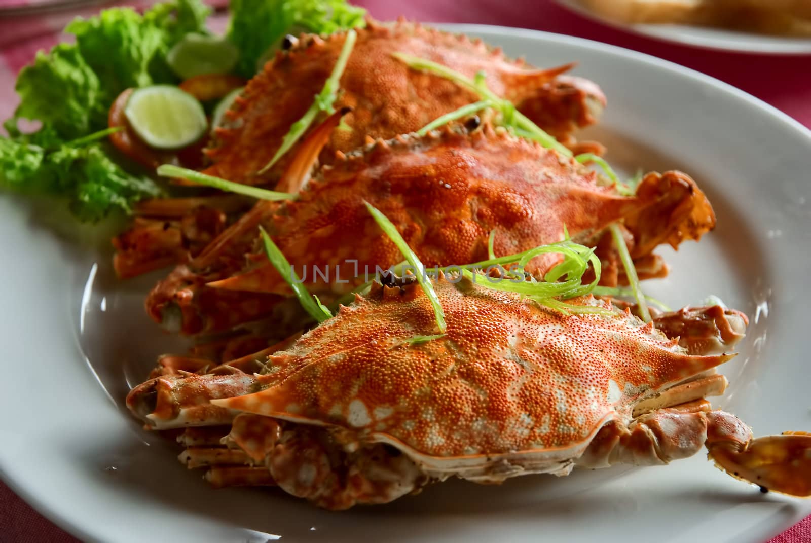 three large red crabs decorated with salad and lime on the plate