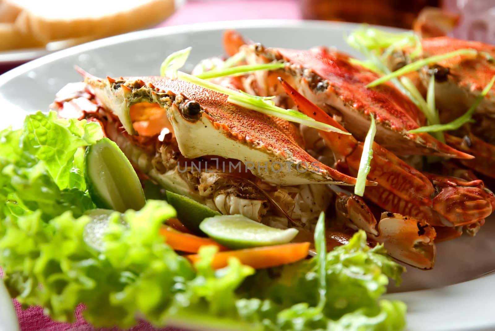 three large red crabs decorated with salad and lime on the plate