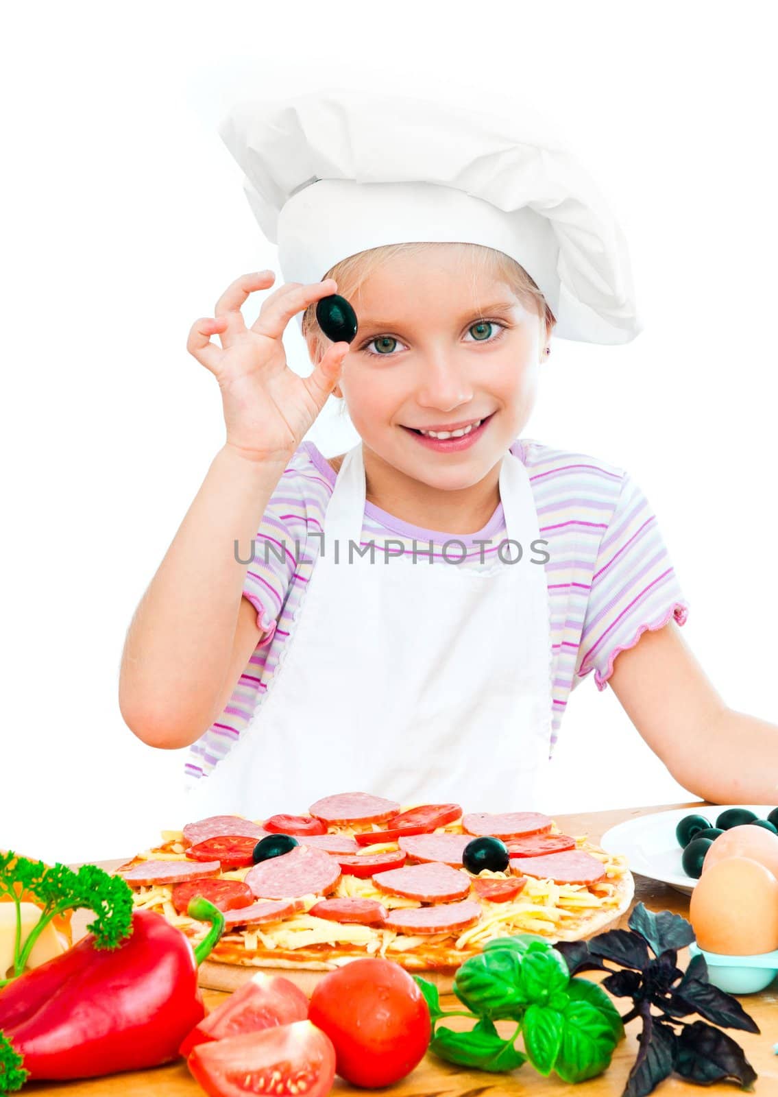 little girl puts olive on a pizza on white background