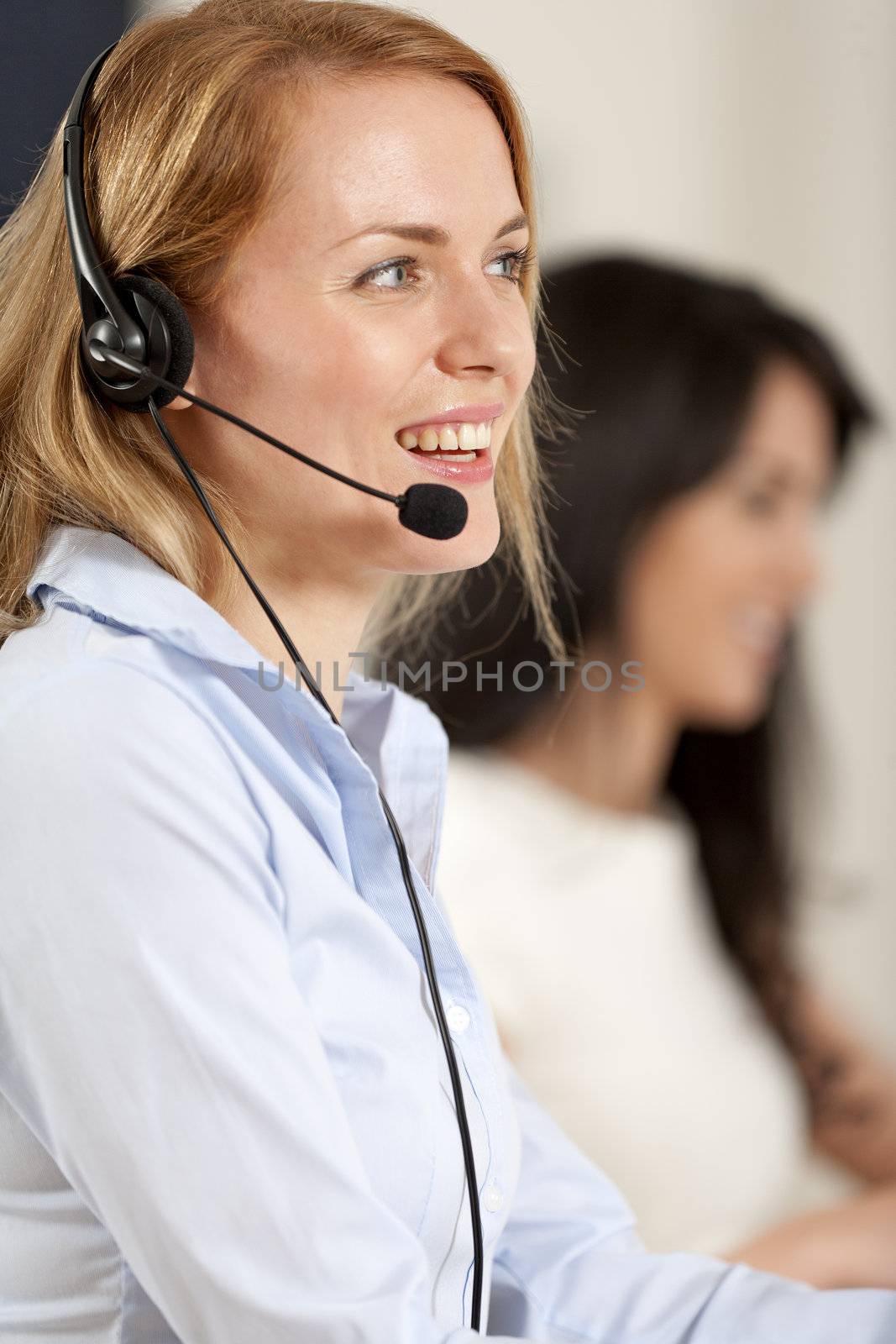 Two colleagues working in a busy call centre office.