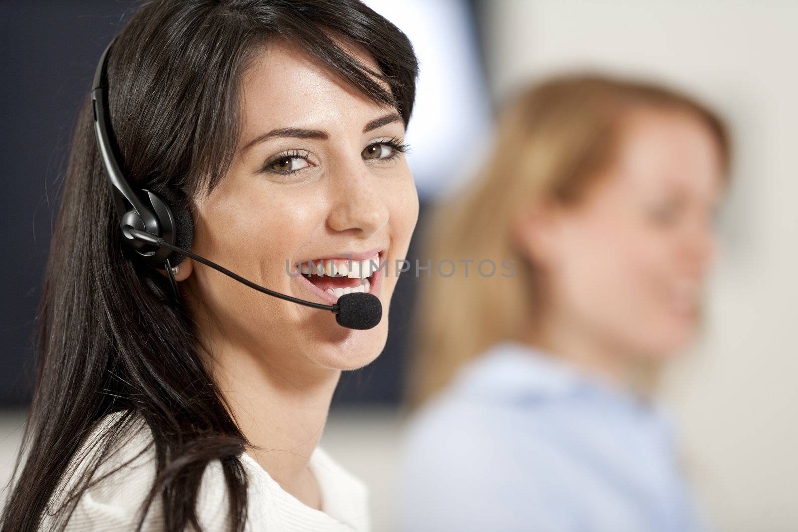 Two colleagues working in a busy call centre office.