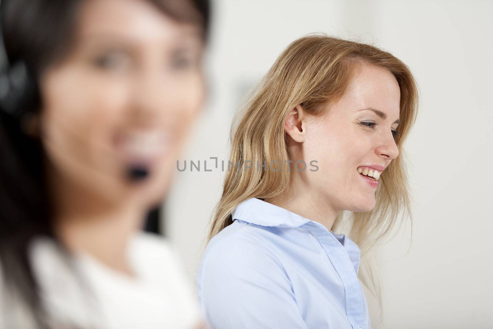 Two colleagues working in a busy call centre office.