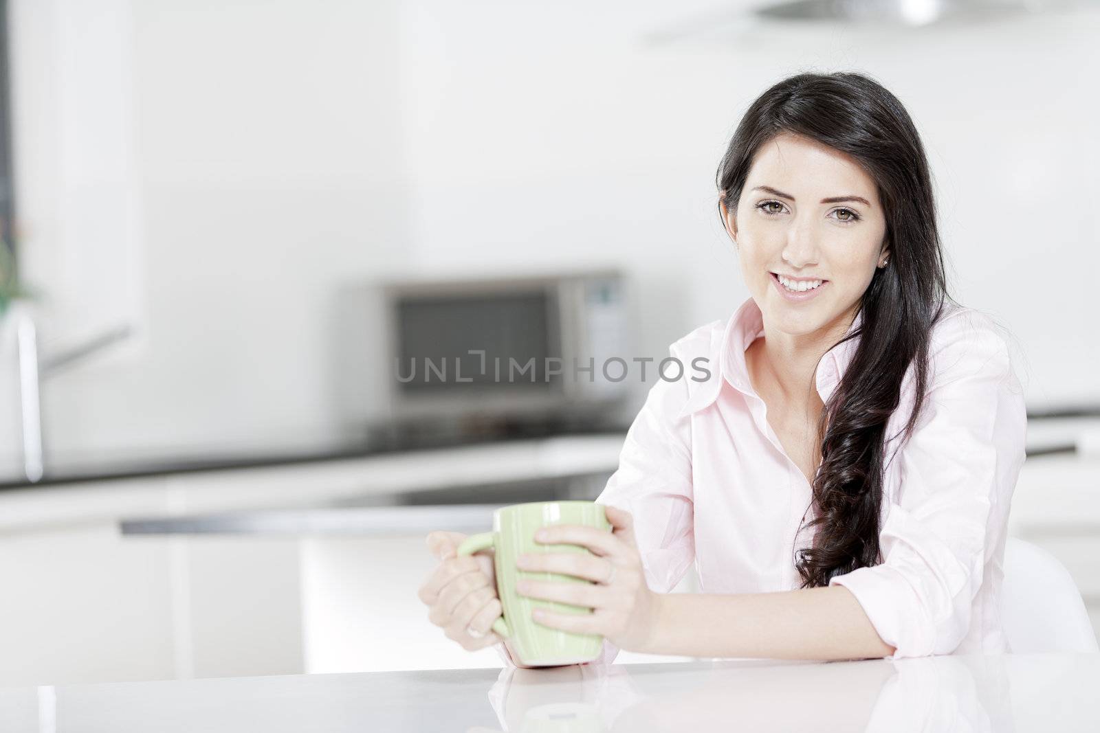 Young woman sat at table with drink by studiofi