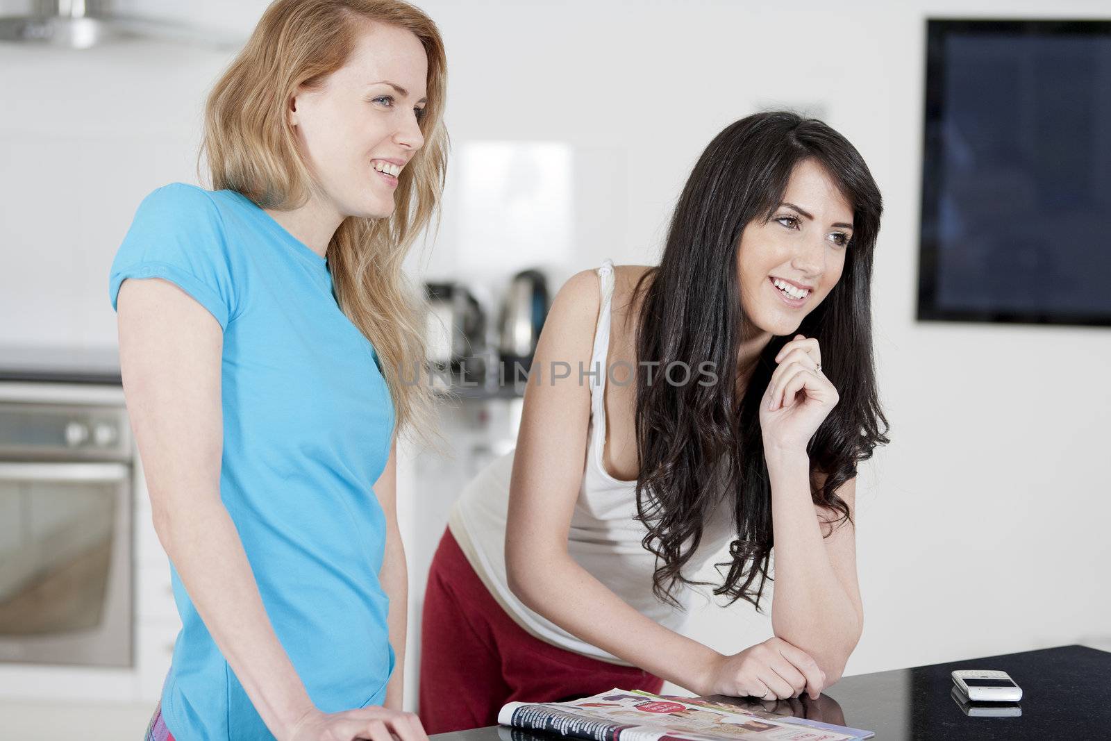 Two young woman chatting and sharing a magazine