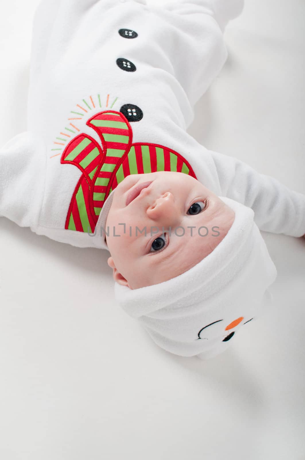 Baby boy in snowman costume watching on you, light background