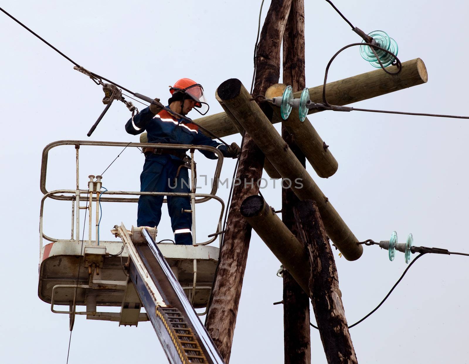 Electrician connects wires on the power line by AleksandrN